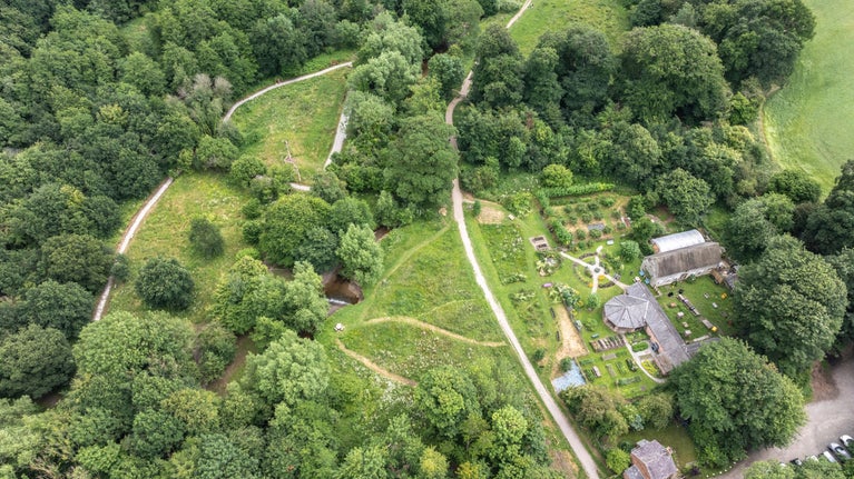 An aerial view of the Mindful Meadow and Mindful Garden at Erddig, Wrexham, with winding paths, trees, and the buildings and nature garden at Felin Pulston